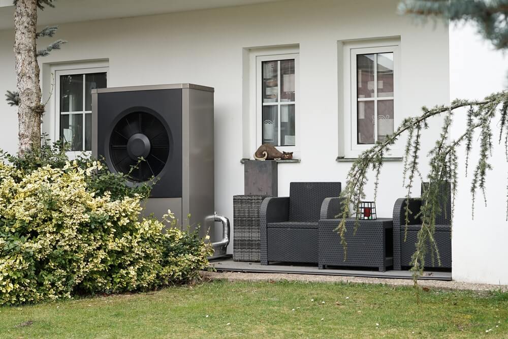 Wärmepumpe Außengerät im Garten vor einem Einfamilienhaus